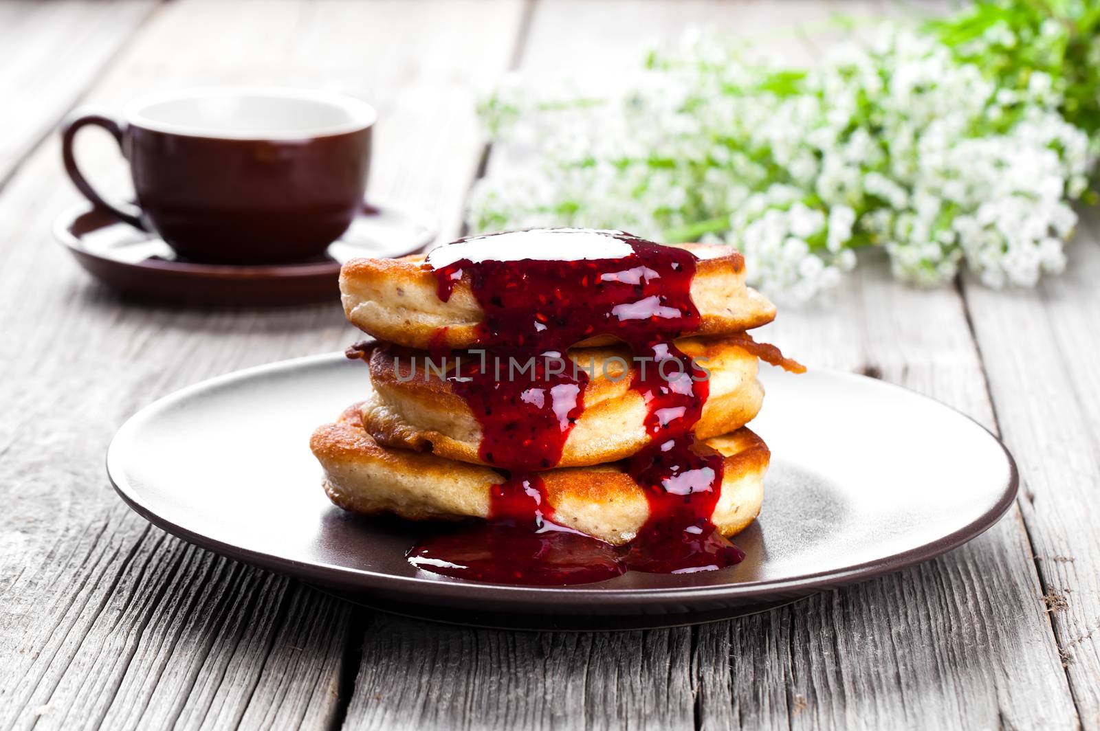 Delicious pancakes with raspberries sauce on the wooden kitchen table