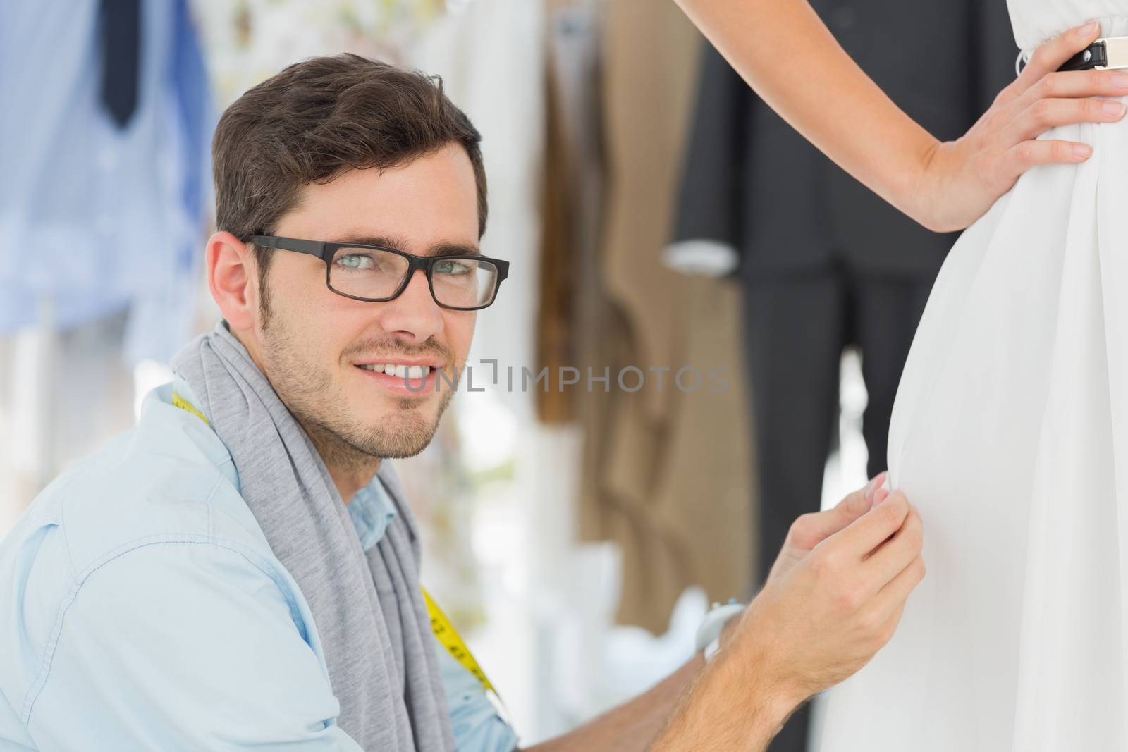Male fashion designer adjusting dress on model by Wavebreakmedia