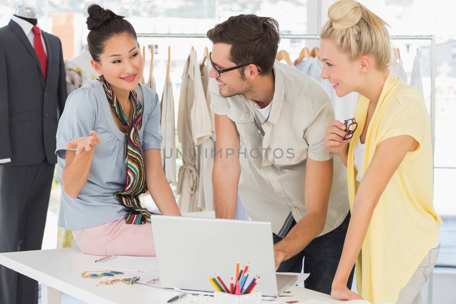 Three fashion designers using laptop in a studio