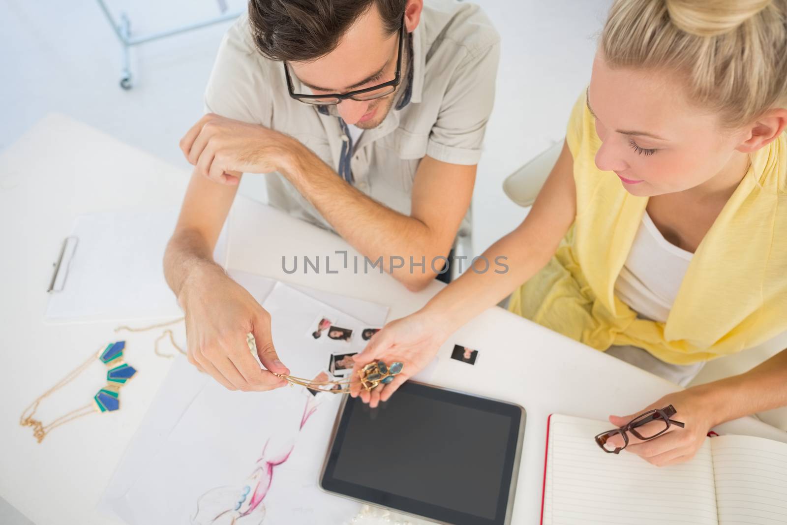 Overhead view of two fashion designers using digital laptop in a studio