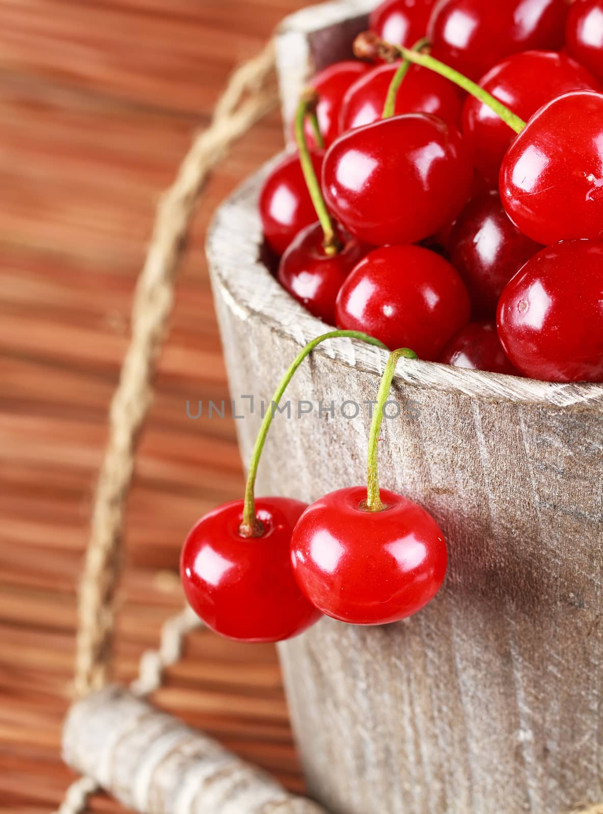 Fresh cherries with water drops in a wood bucket by Bedolaga