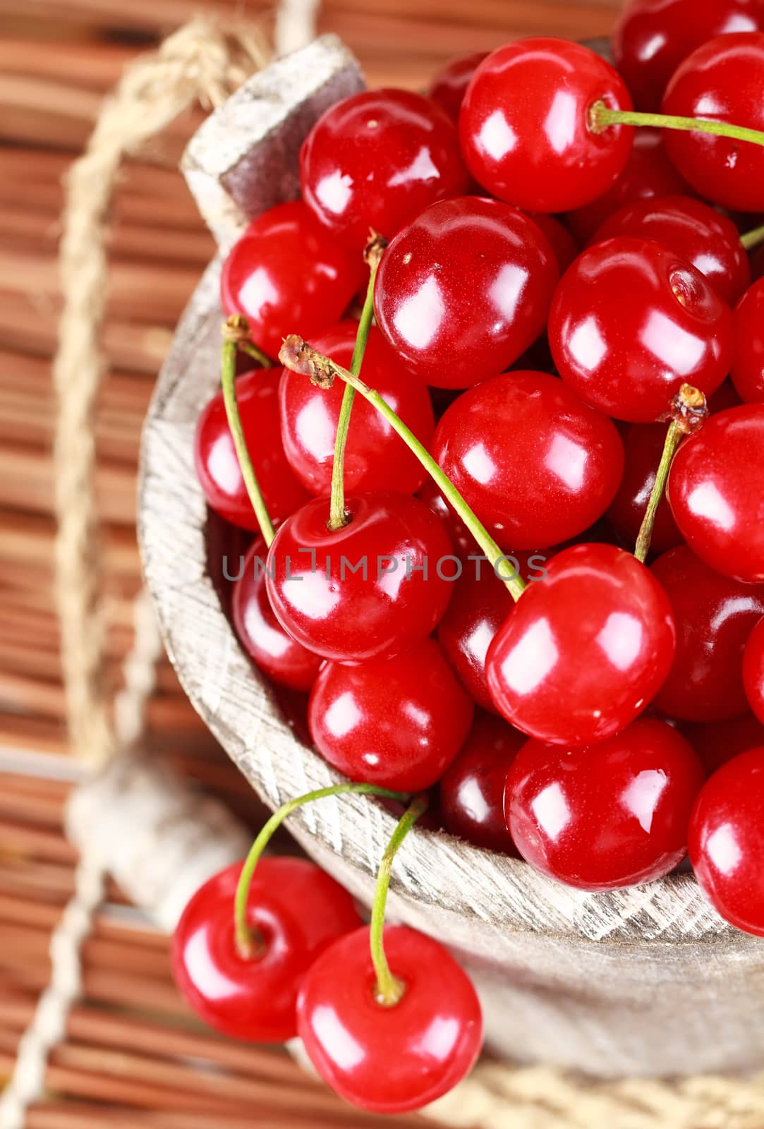 Fresh cherries with water drops in a wood bucket