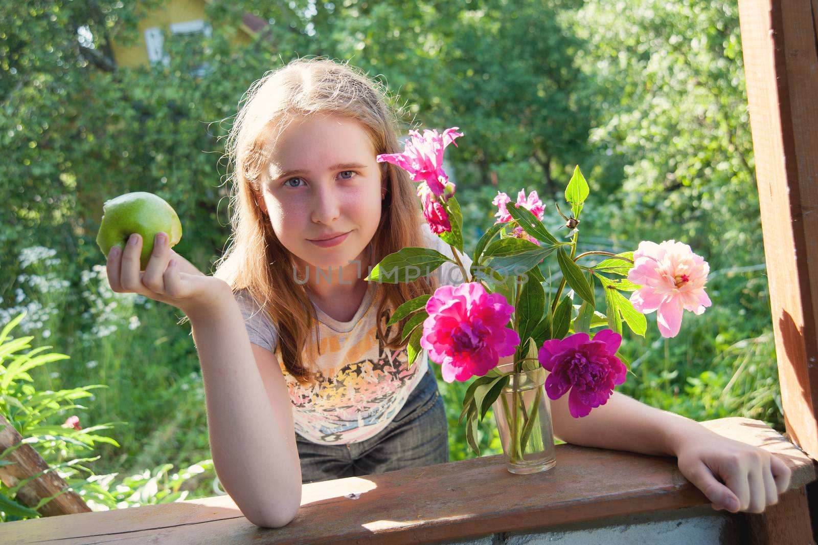  girl with an Apple and a bouquet of peonies at a dacha in the summer