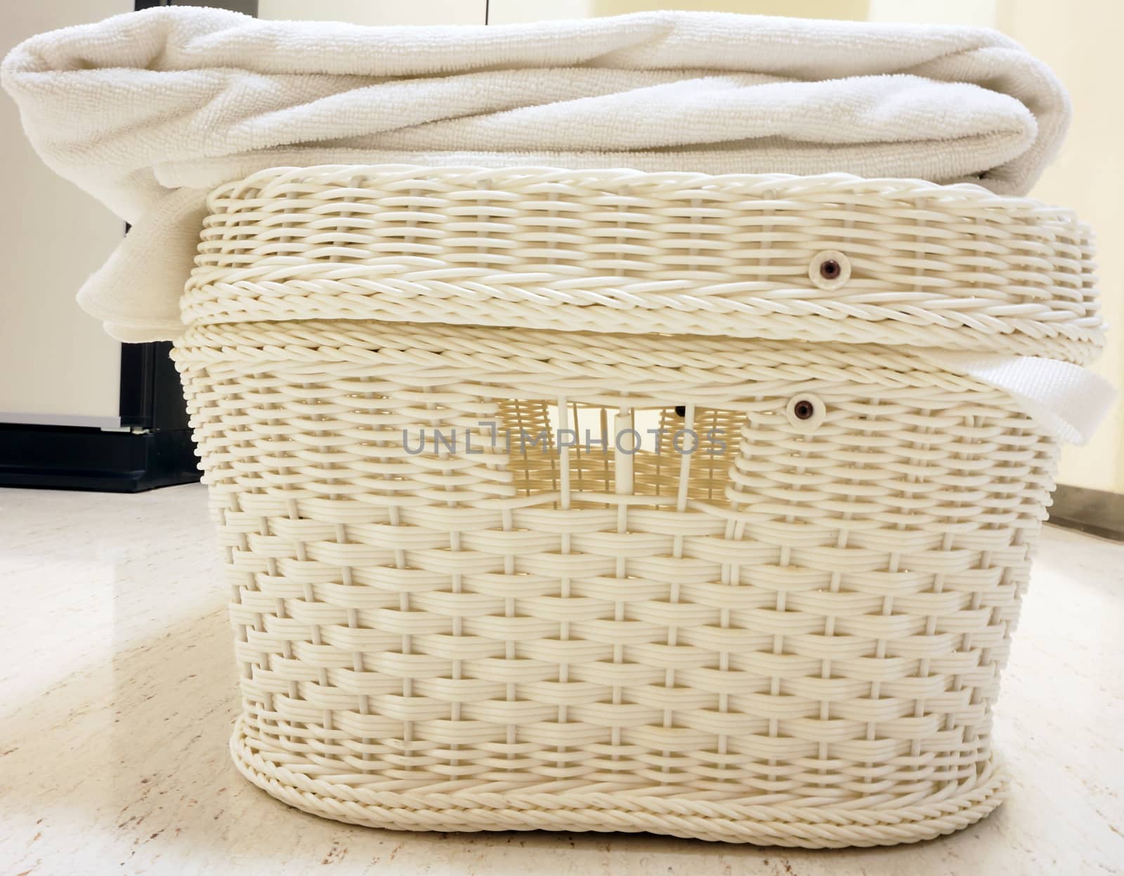 White basket with a lid. Used for clothes placed on the table in hotel.                                