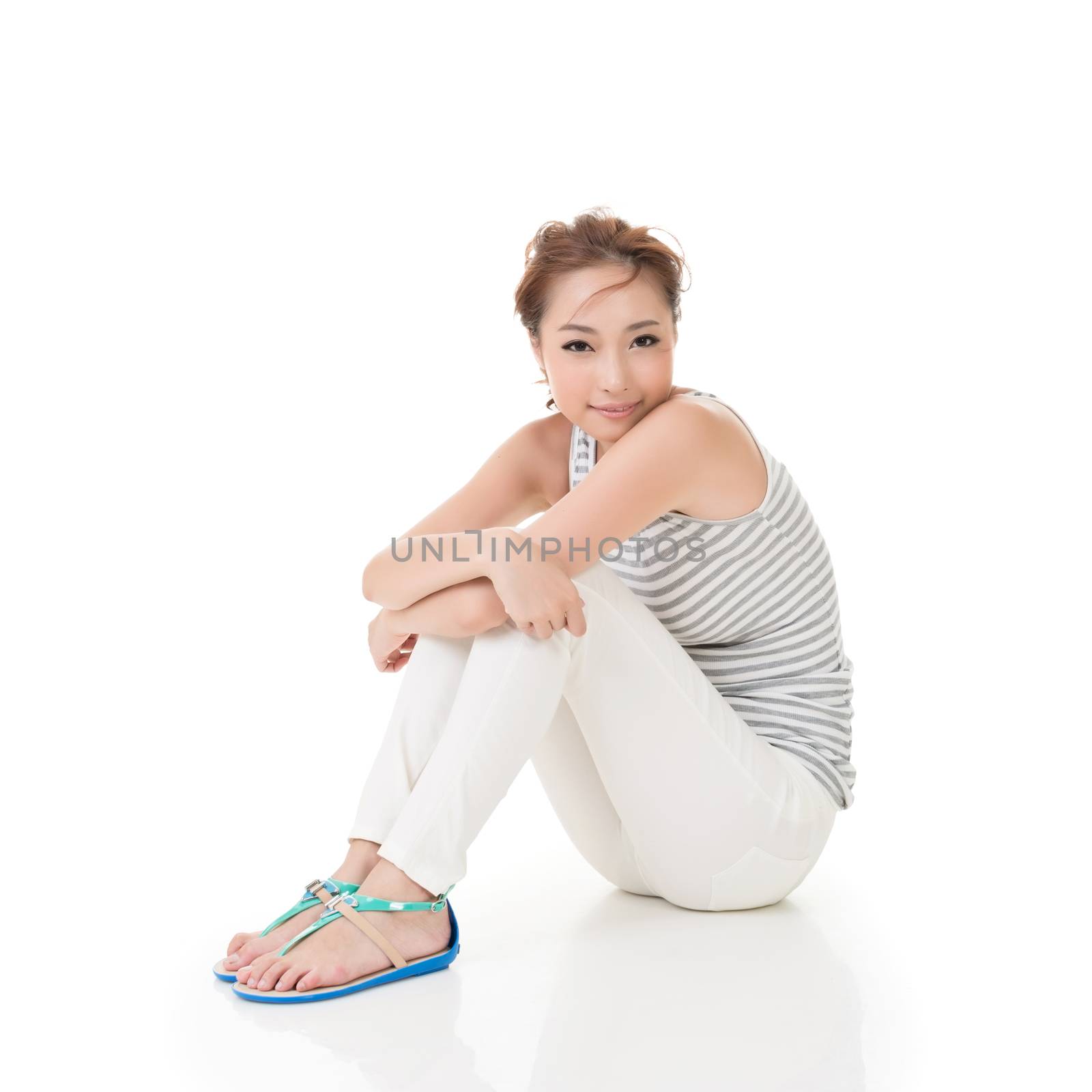 Attractive asian woman sit on ground and looking to the camera. Full length portrait isolated on the white background.