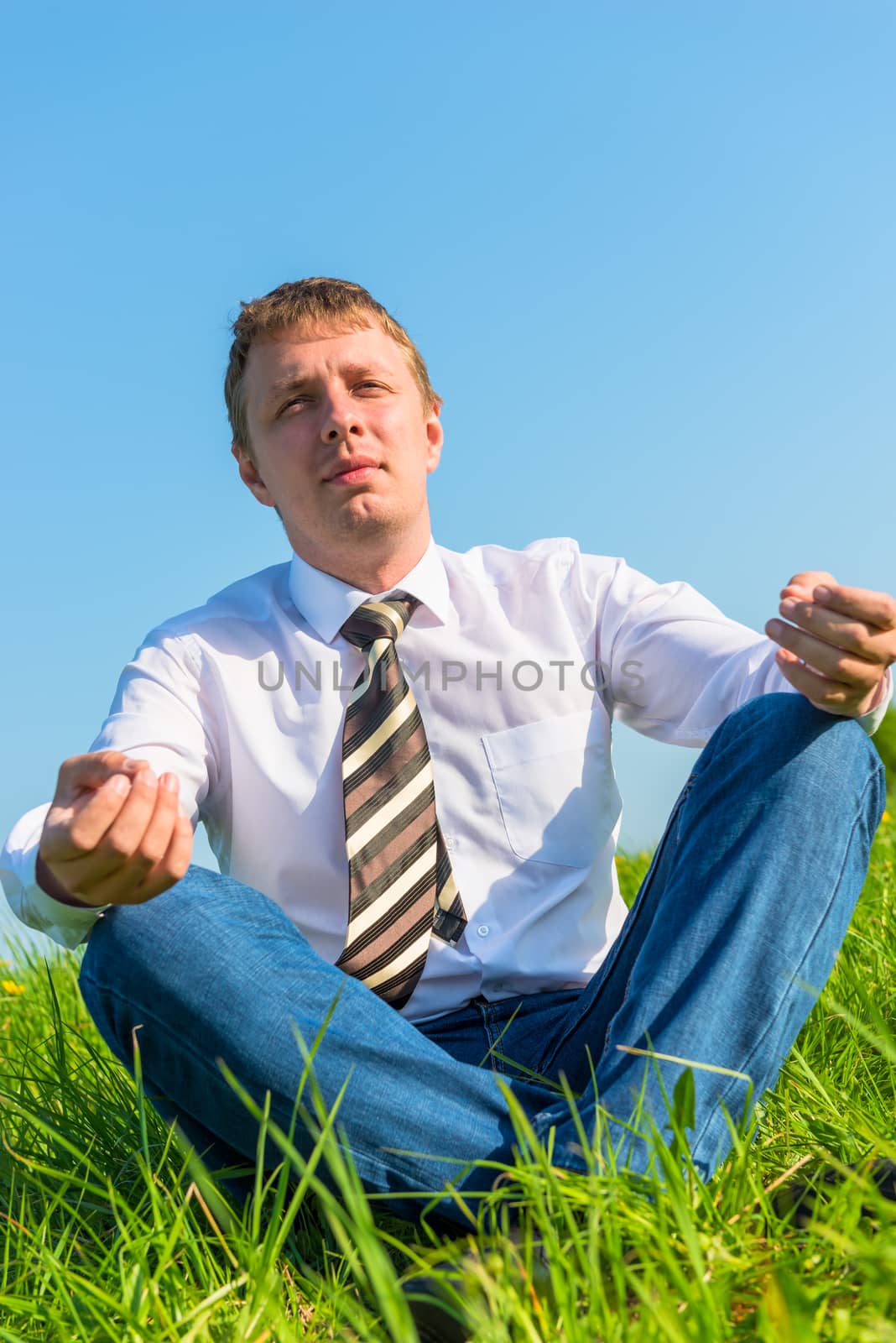 happy businessman relaxes in a field in the lotus position by kosmsos111