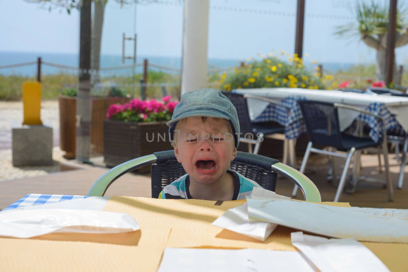 Unhappy crying baby boy sitting on the table