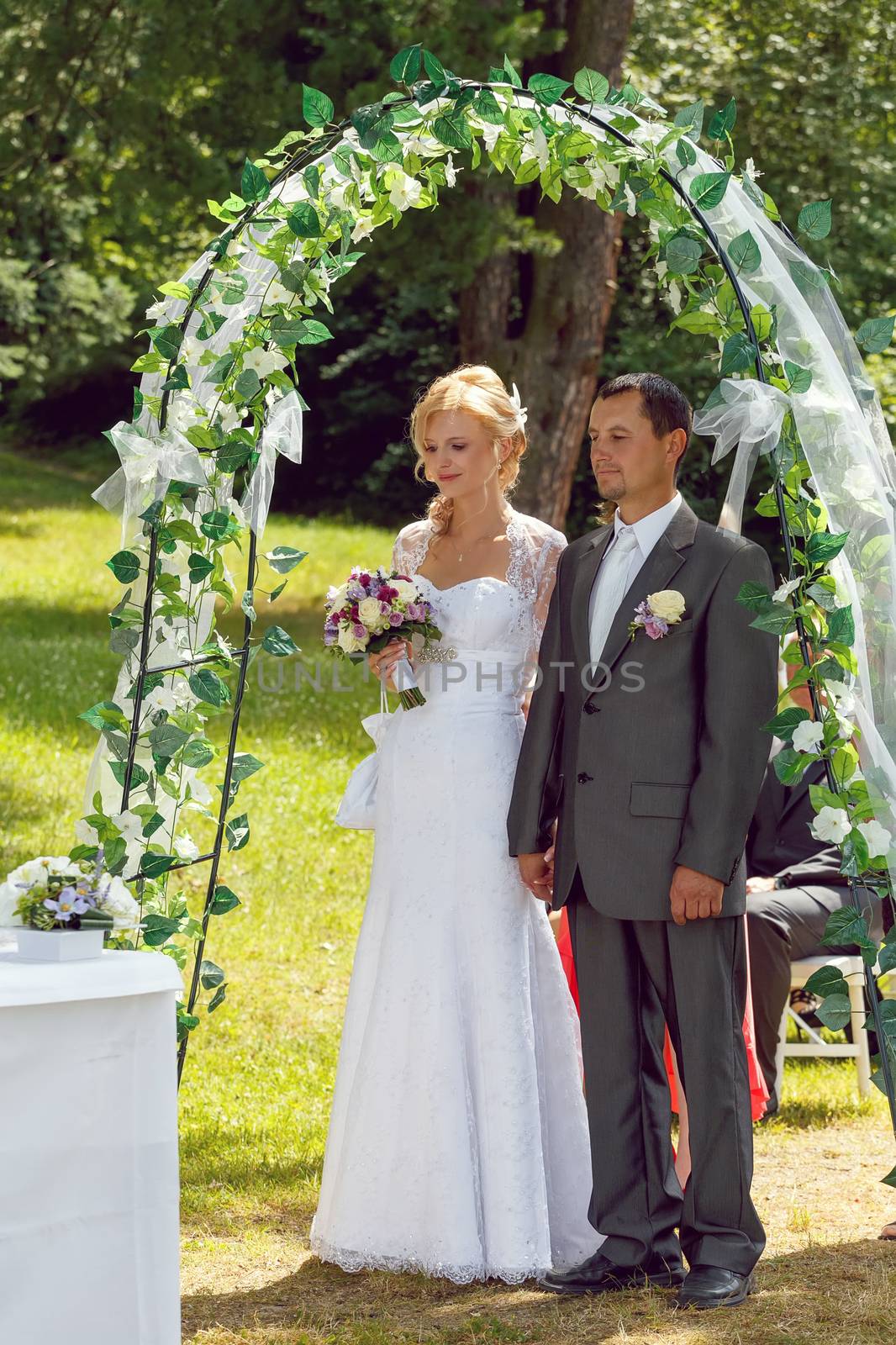 beautiful young couple in wedding ceremony outdoor, blonde bride with flower and groom