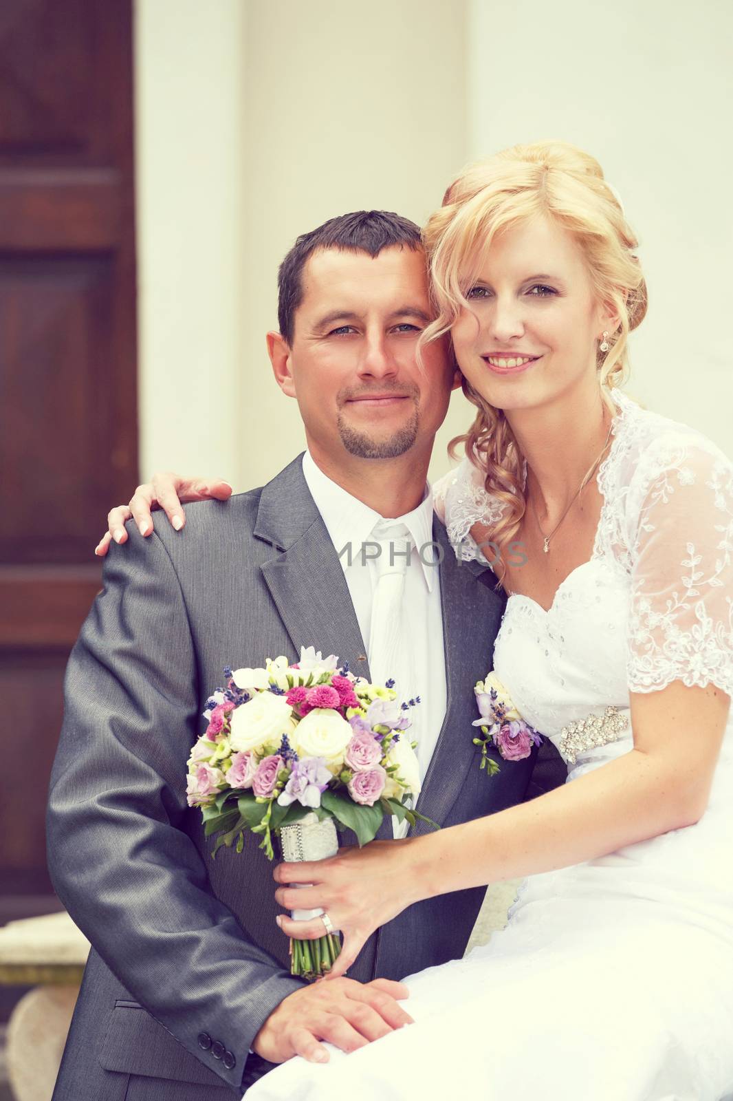 beautiful young wedding couple, blonde bride with flower and her groom, retro color tone