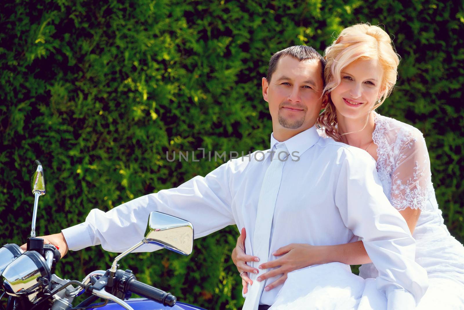 beautiful young wedding couple, blonde bride with flower on motorcycle with her groom