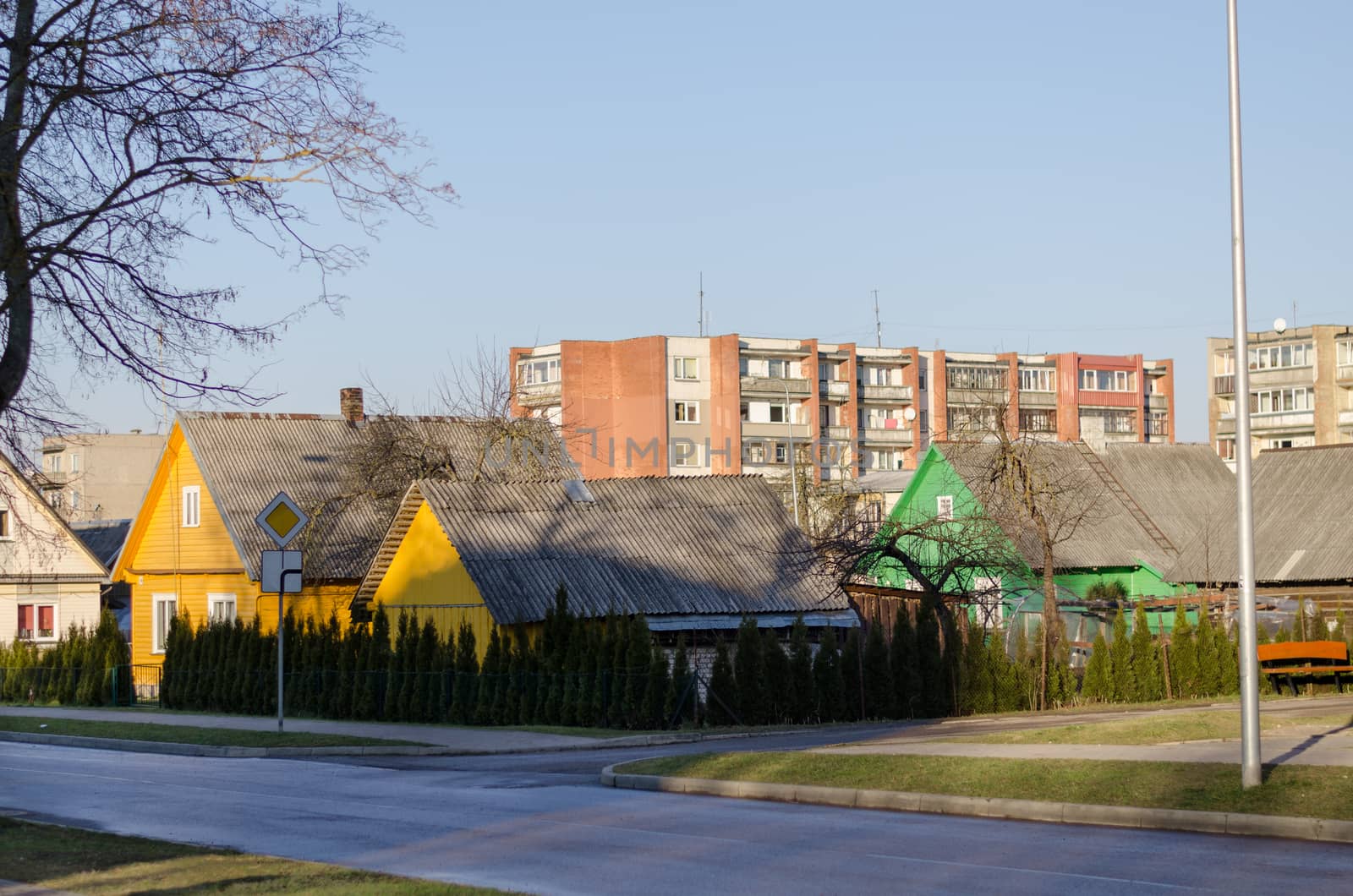 rural style painted wooden houses and multistorey red brick house, country city contrast