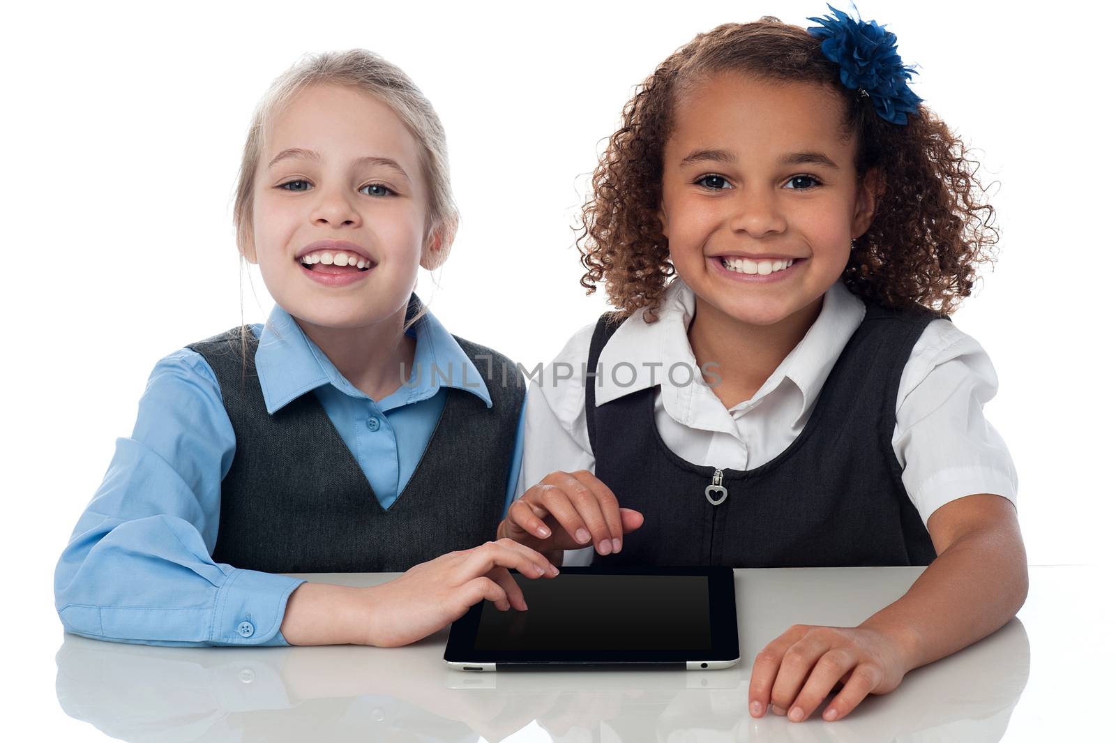 Smiling school girls playing on touchpad by stockyimages