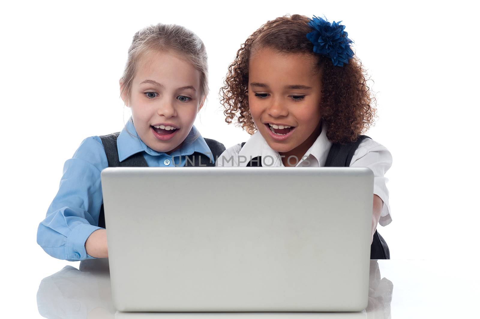 Smiling school girls using laptop together