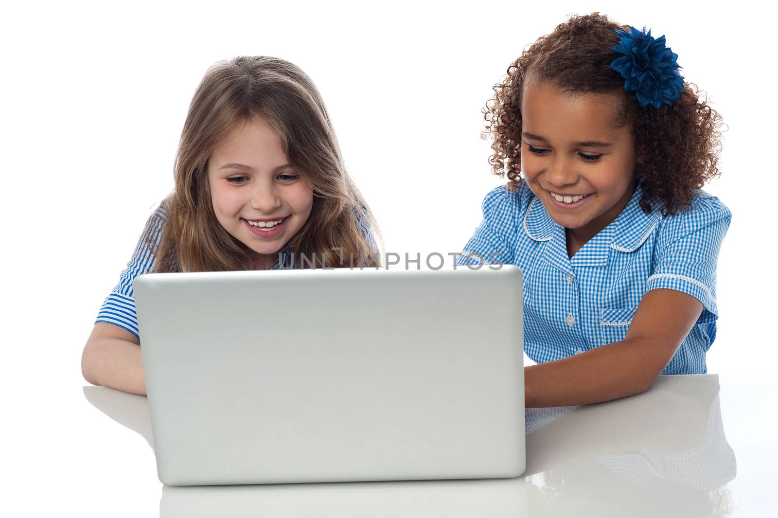 Smiling school girls using laptop together