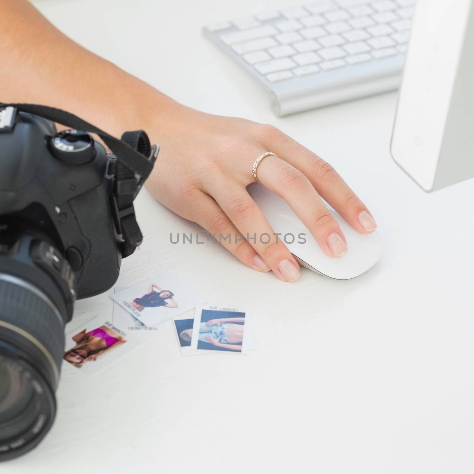 Digital camera on photographers desk with womans hand on mouse by Wavebreakmedia