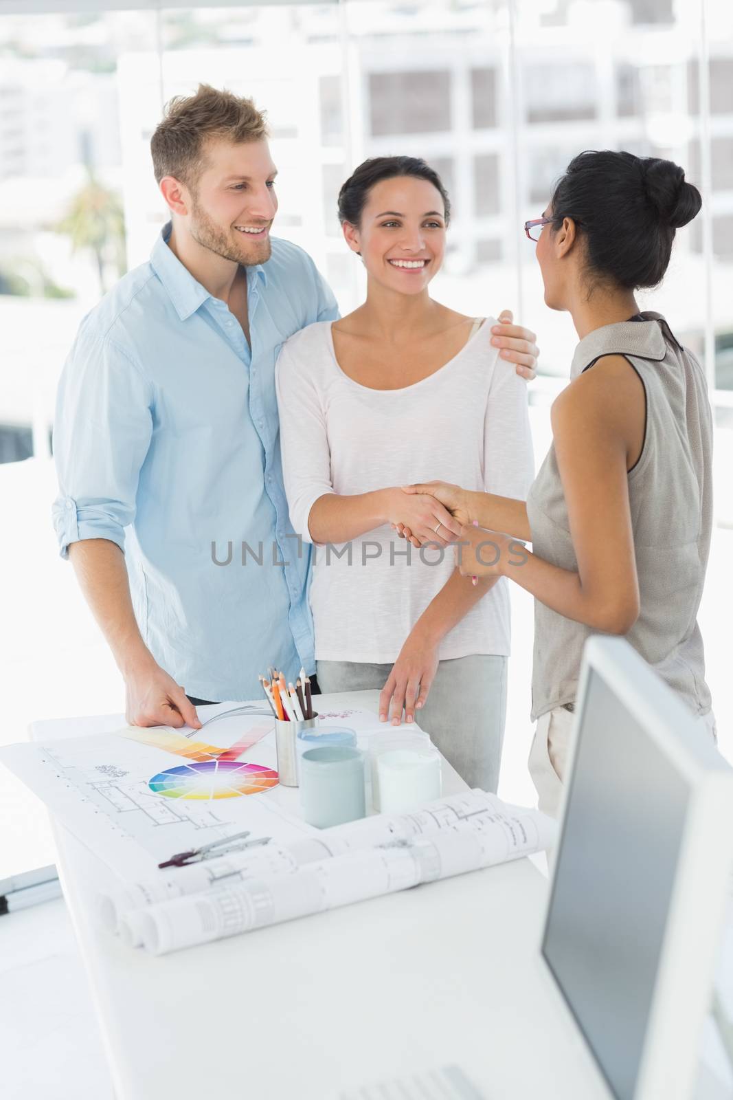 Interior designer shaking hands with smiling client in her studio