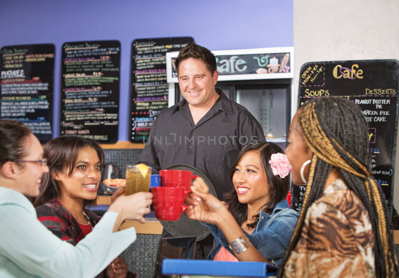 Happy diverse group of people in cafe with waiter