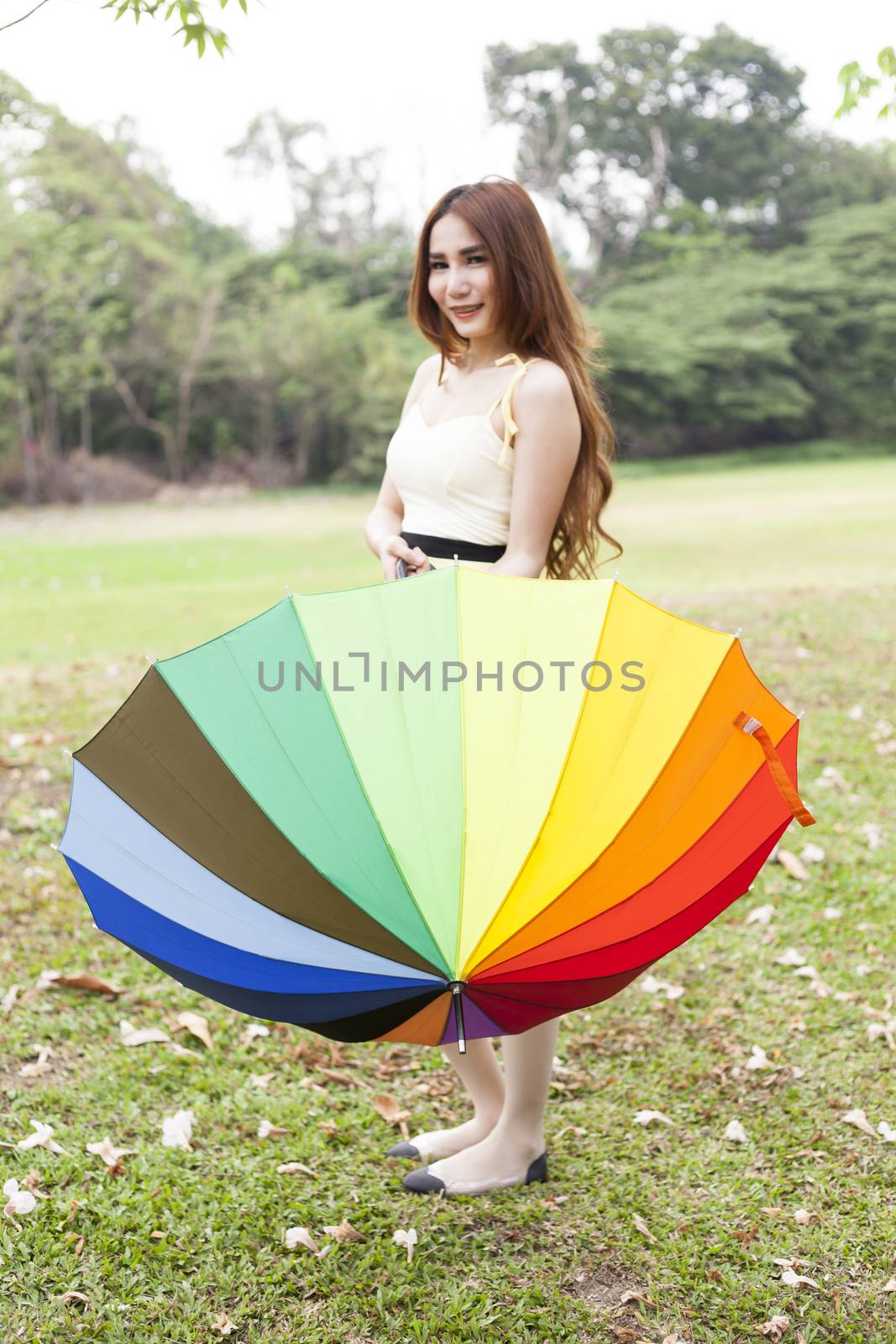 woman standing holding an umbrella On the grass in the park.