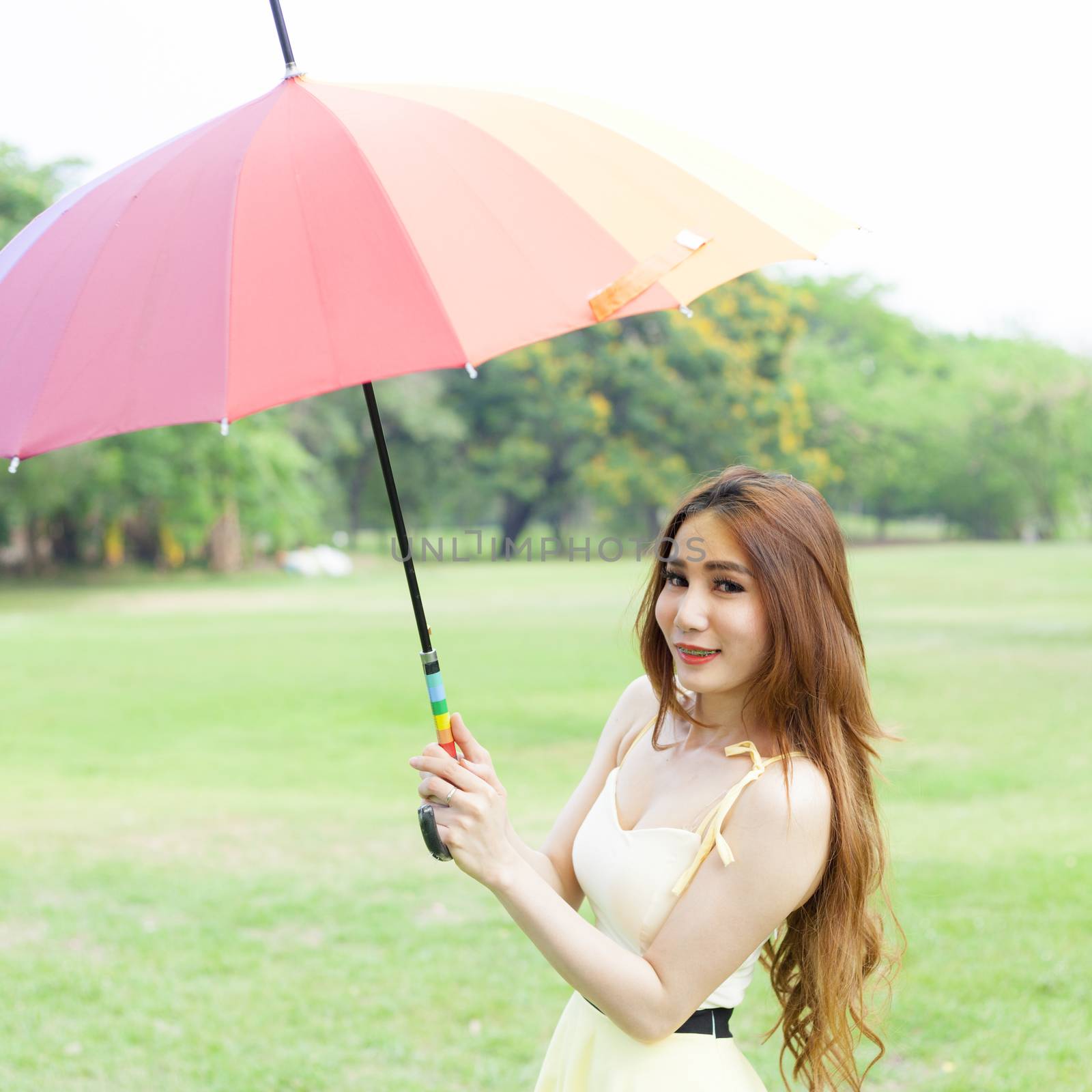 Woman with umbrella standing on the lawn. In the park during the day, the sun is strongest.