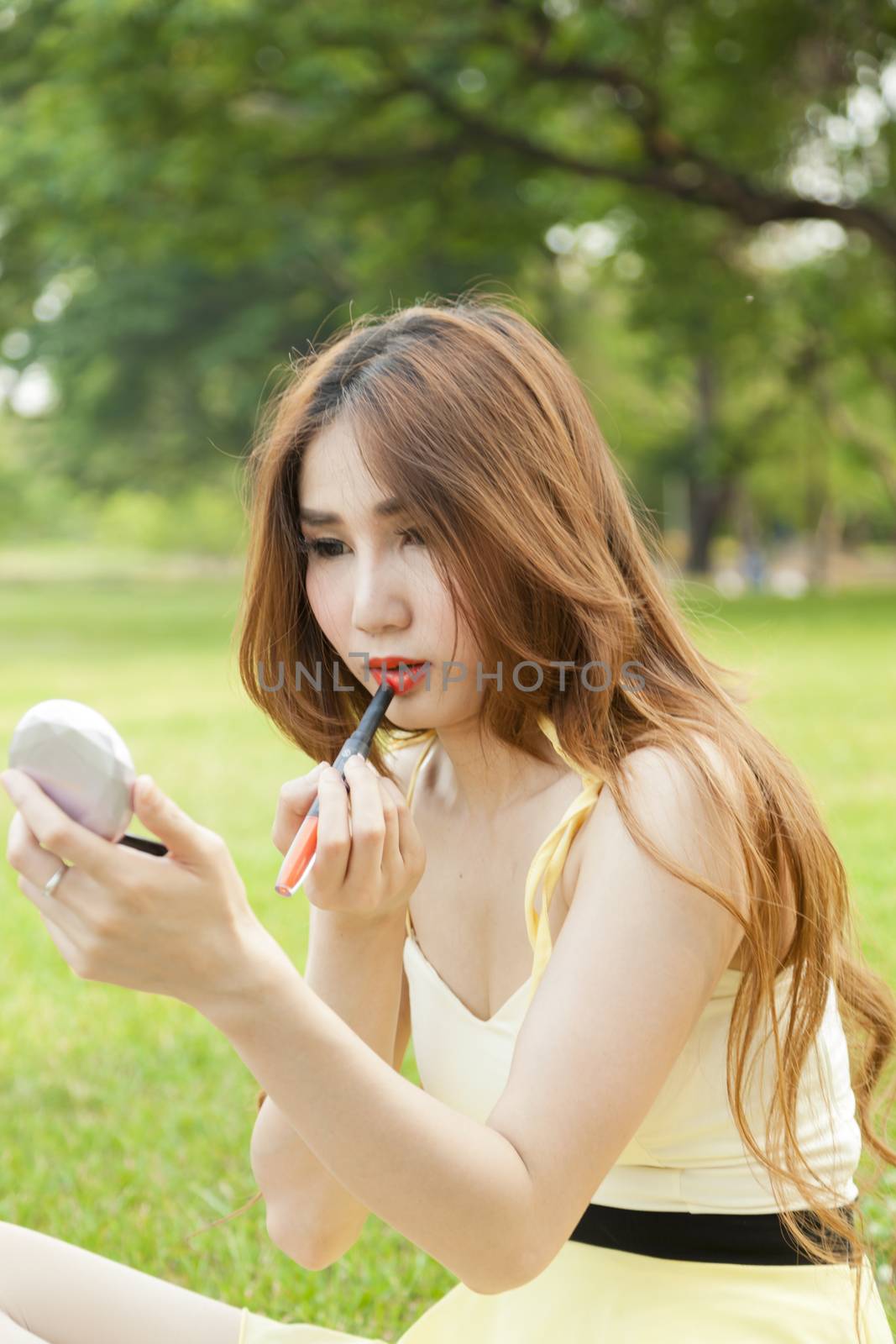 Woman in makeup Are lipstick and sitting on the lawn.