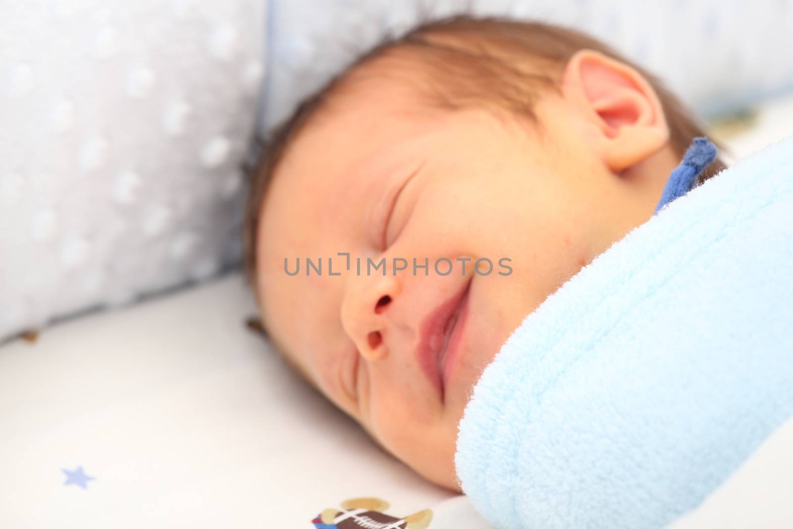 Blanket covering a newborn smiling. Focus in the blanket.