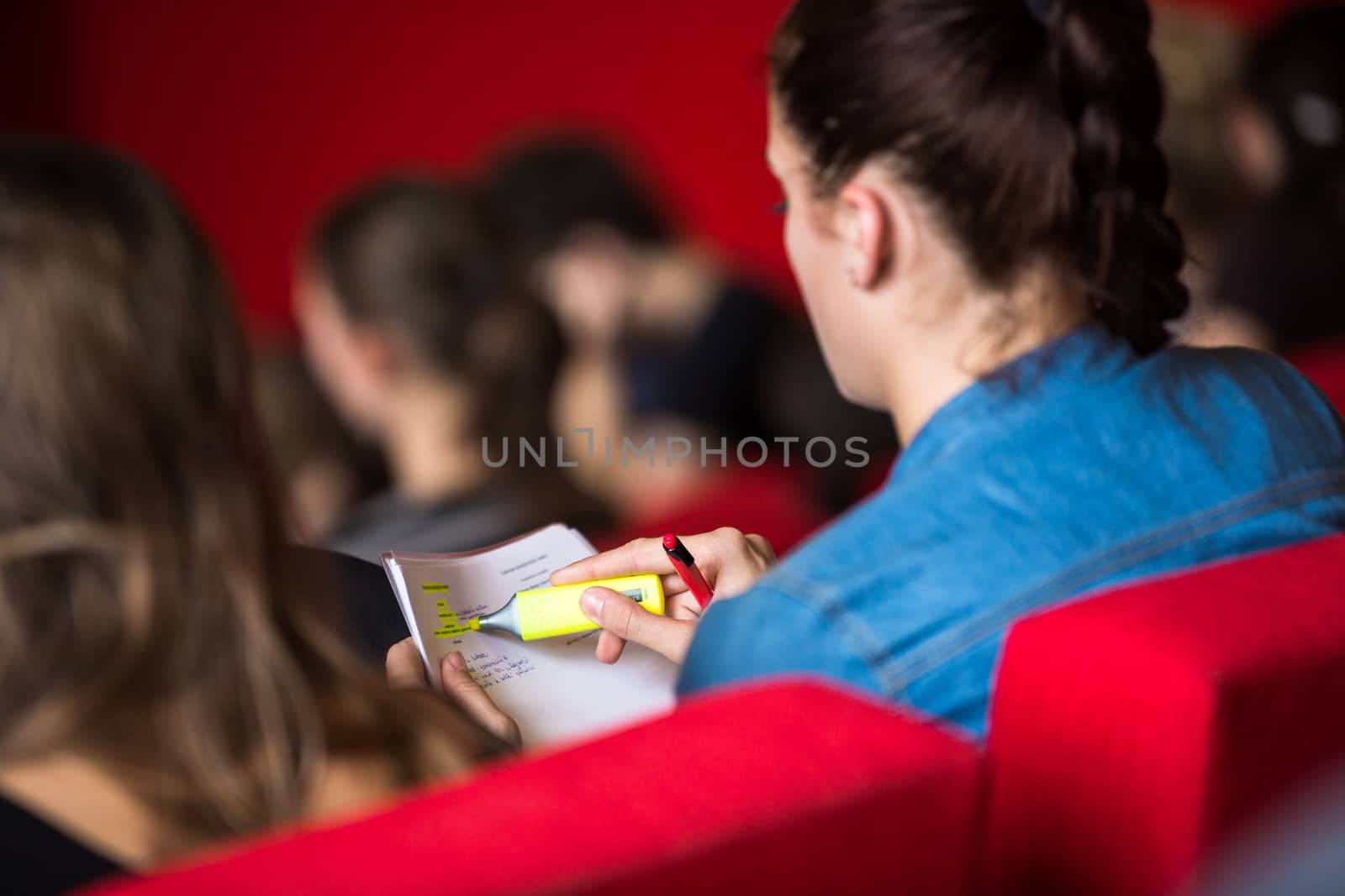 Female university student sitting in class, taking notes by viktor_cap
