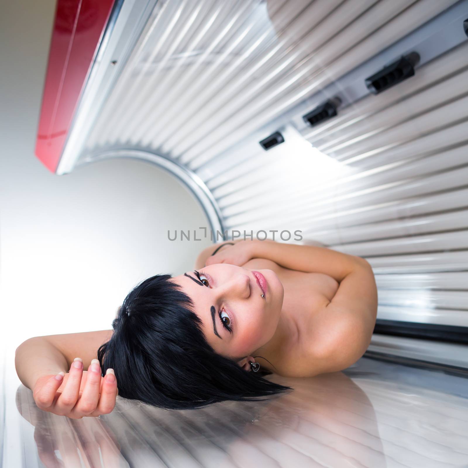 Pretty young woman tanning her skin in a modern solarium by viktor_cap