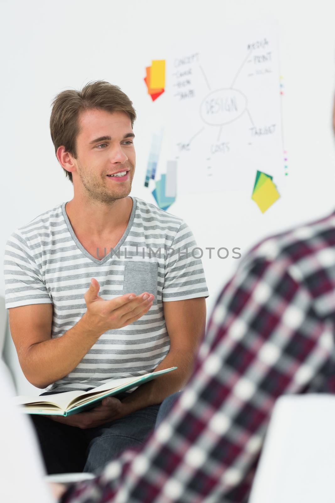 Young man talking to colleagues at a meeting in creative office