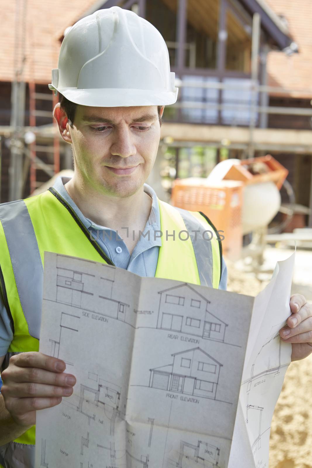 Construction Worker On Building Site Looking At House Plans