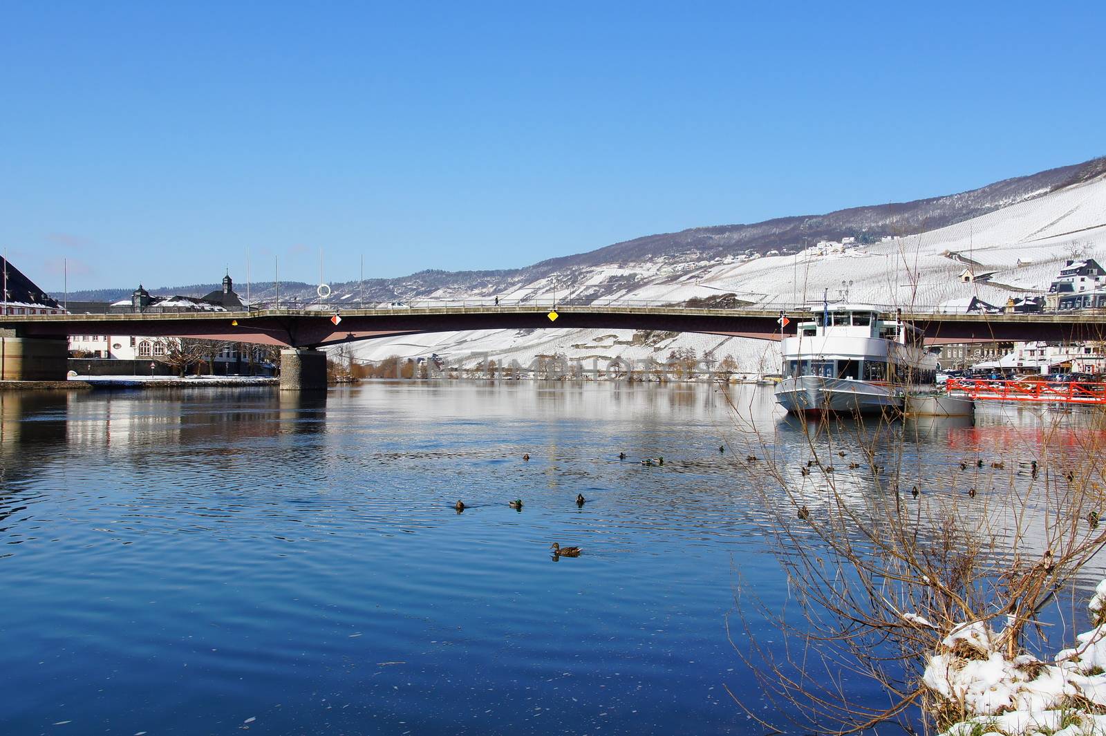 Moselle covered bridge in Bernkastel-Kues in Rhineland-Palatinate in the winter, the vineyards in the background are snowy