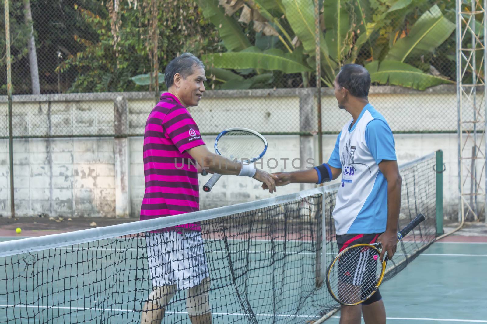 SURAT THANI, THAILAND - MARCH 1:Unidentified Thai senior tennis players shakes the hands after winning the match on March 1, 2014 in Chaiya tennis court, Surat Thani, Thailand.

