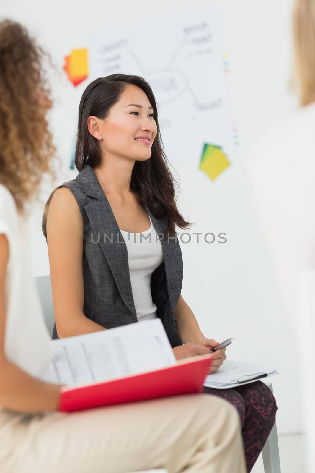 Smiling asian woman listening at a meeting in creative office