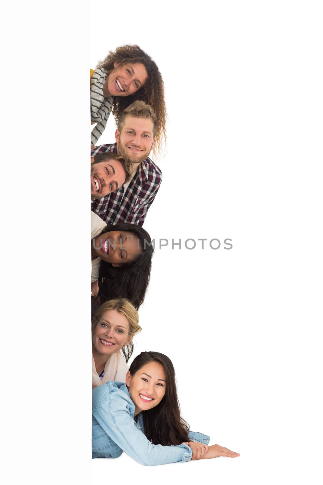 Happy group of young friends peeking from behind a wall by Wavebreakmedia