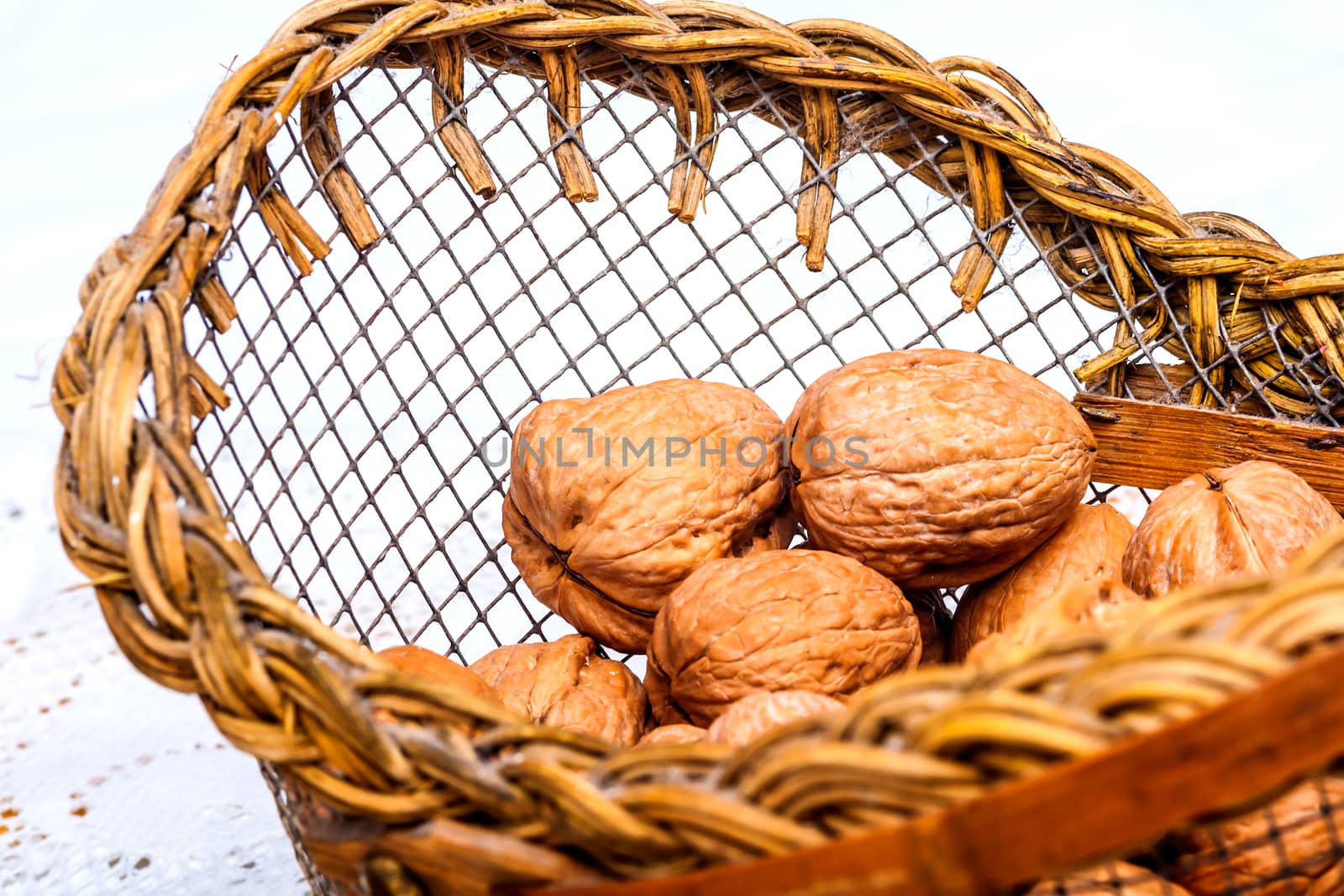 A composition of walnuts on a basket over a white background