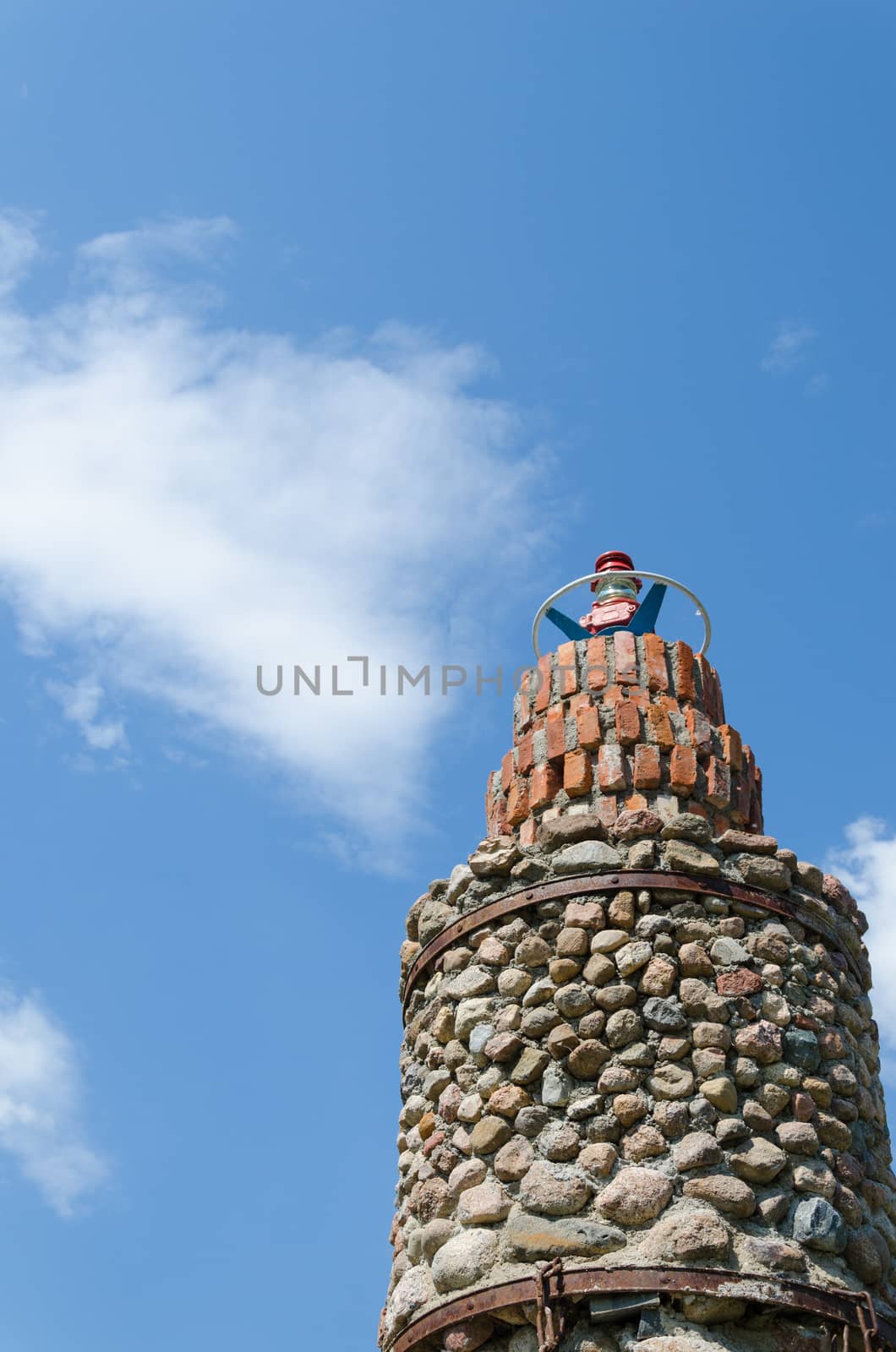 cobblestone lighthouse tower on blue sky background