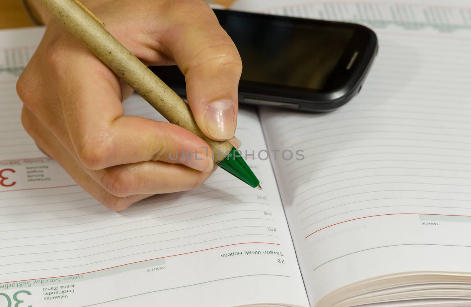 Business woman hand with pen make write notes in notebook and mobile smart phone.