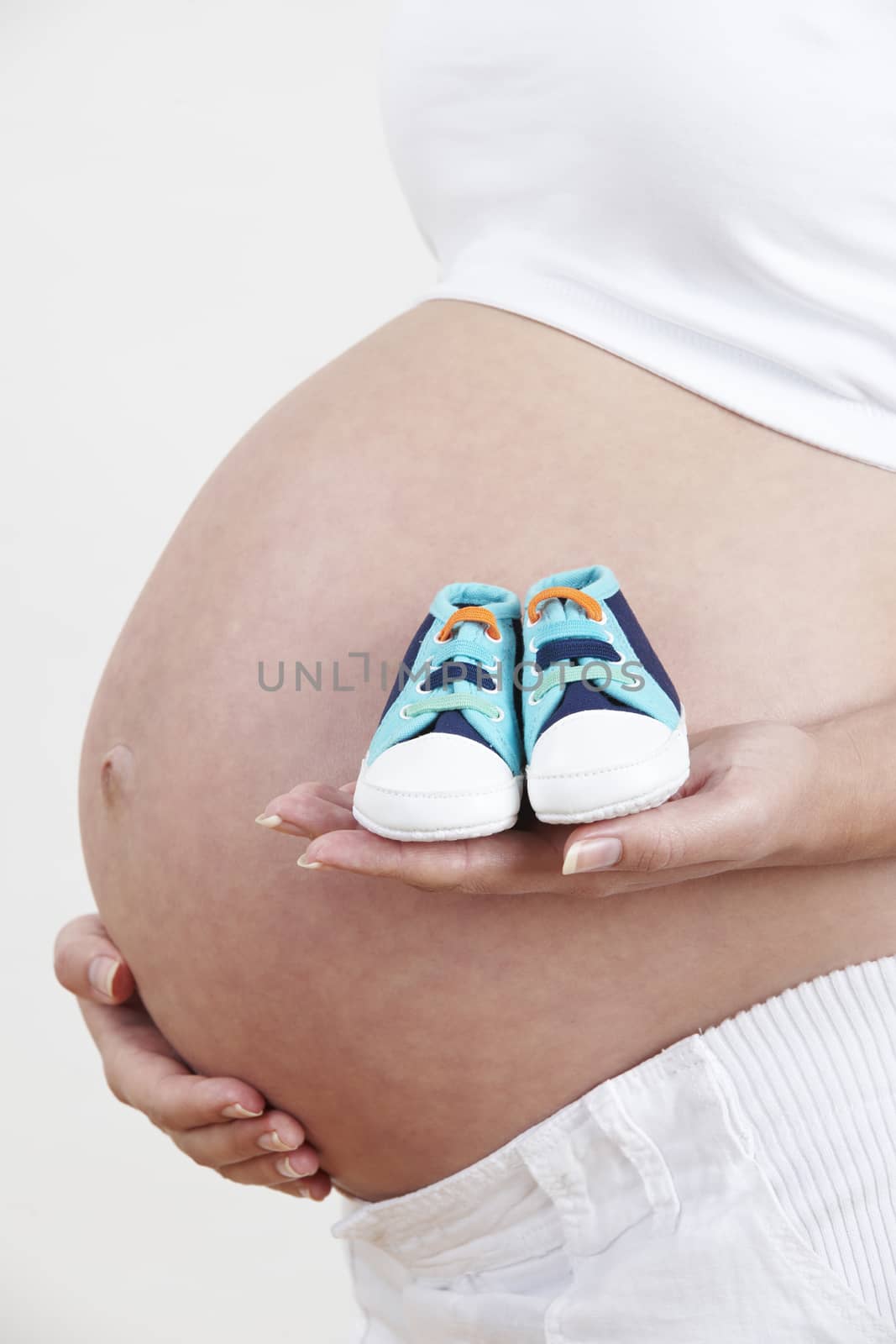 Close Up Of Pregnant Woman Holding Baby Shoes