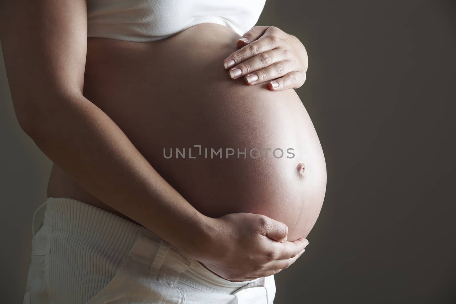 Low Key Image Of Pregnant Woman Holding Belly