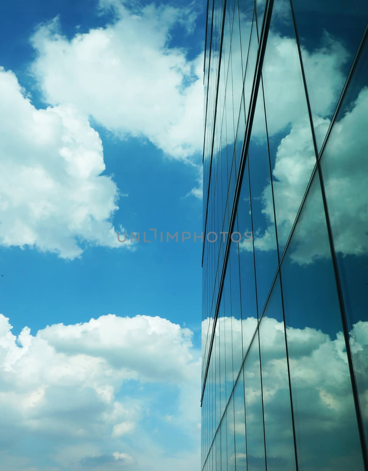 Tall buildings with modern style creating a mirror, reflecting the light from outside the building, reflecting  the clouds that floating by and the beautiful of blue sky.                              