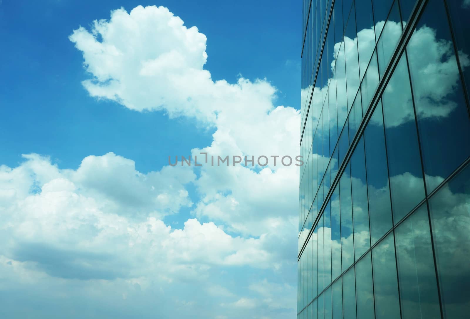 Tall buildings with modern style creating a mirror, reflecting the light from outside the building, reflecting  the clouds that floating by and the beautiful of blue sky.                               