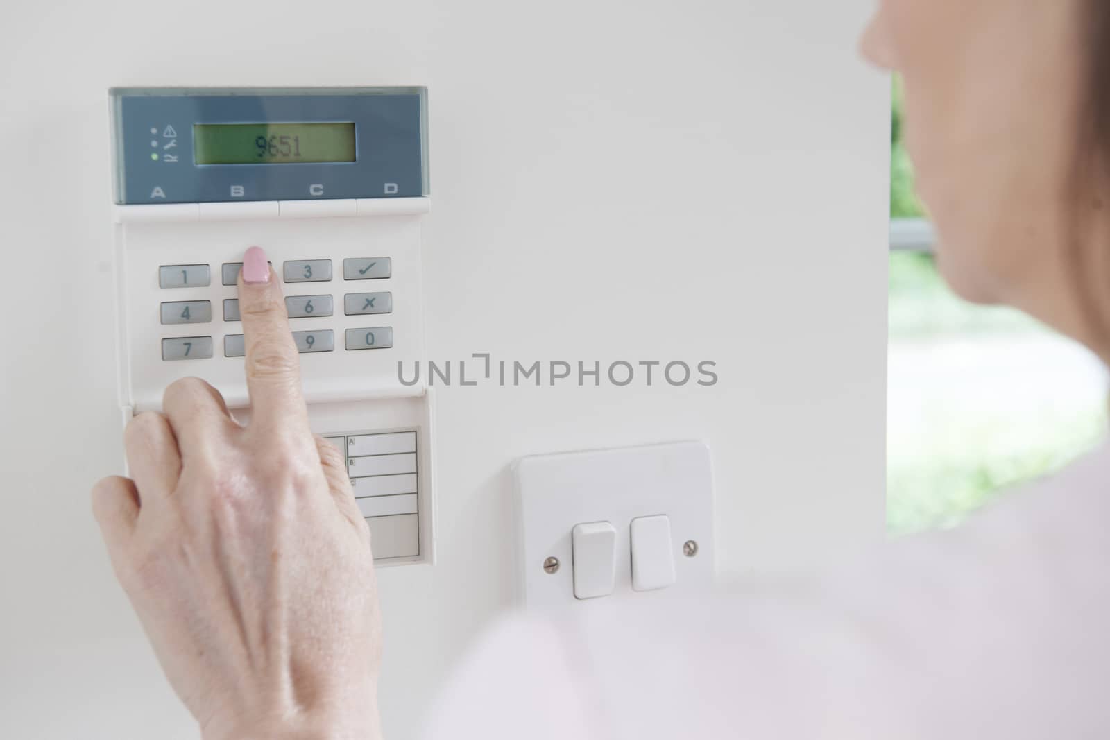 Woman Setting Control Panel On Home Security System by HighwayStarz