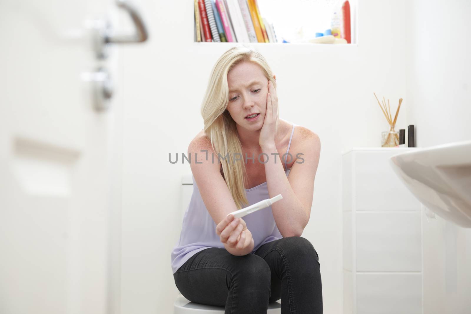Worried Teenage Girl Sitting In Bathroom With Pregnancy Test by HighwayStarz