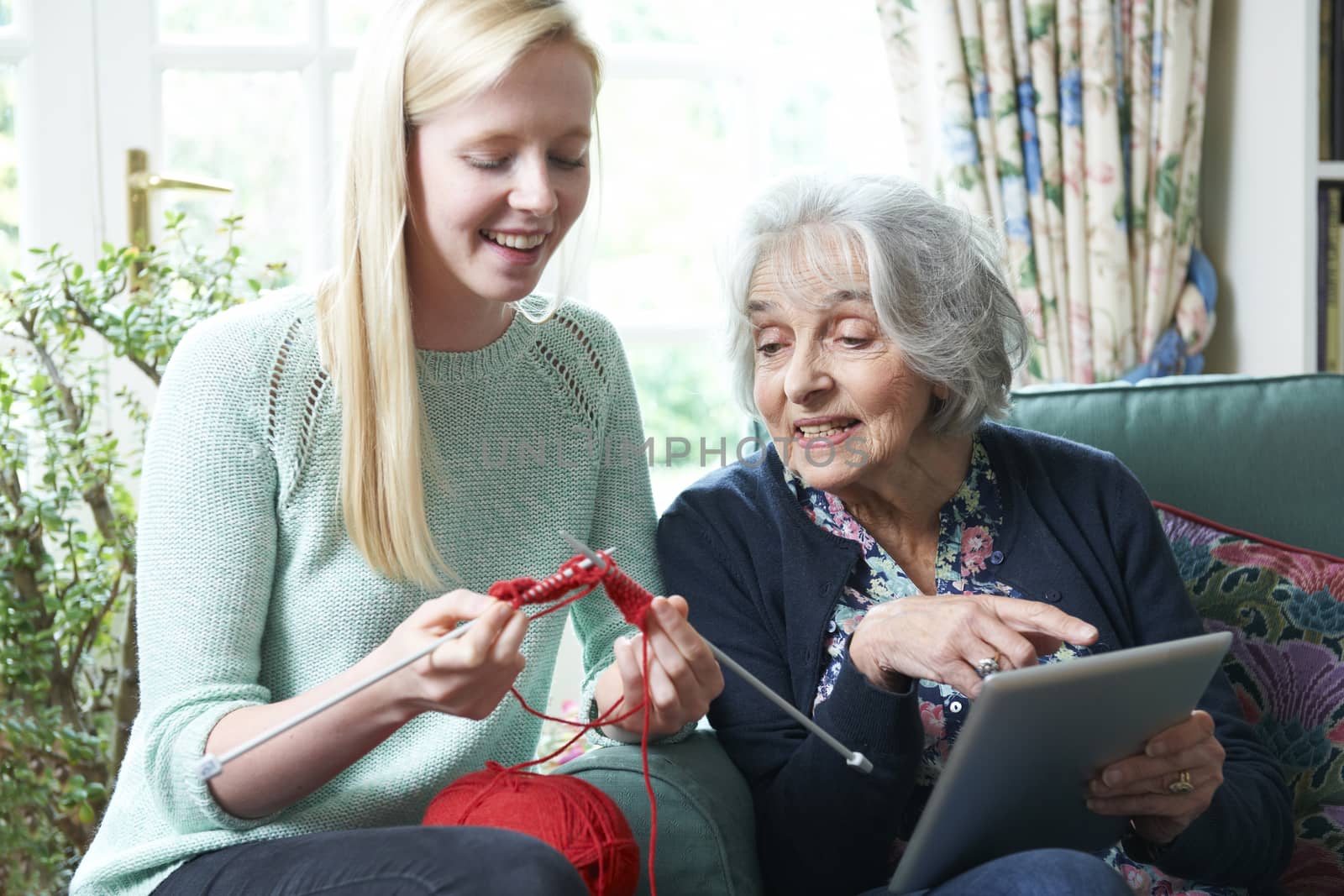 Grandmother With Digital Tablet Showing Granddaughter How To Knit by HighwayStarz