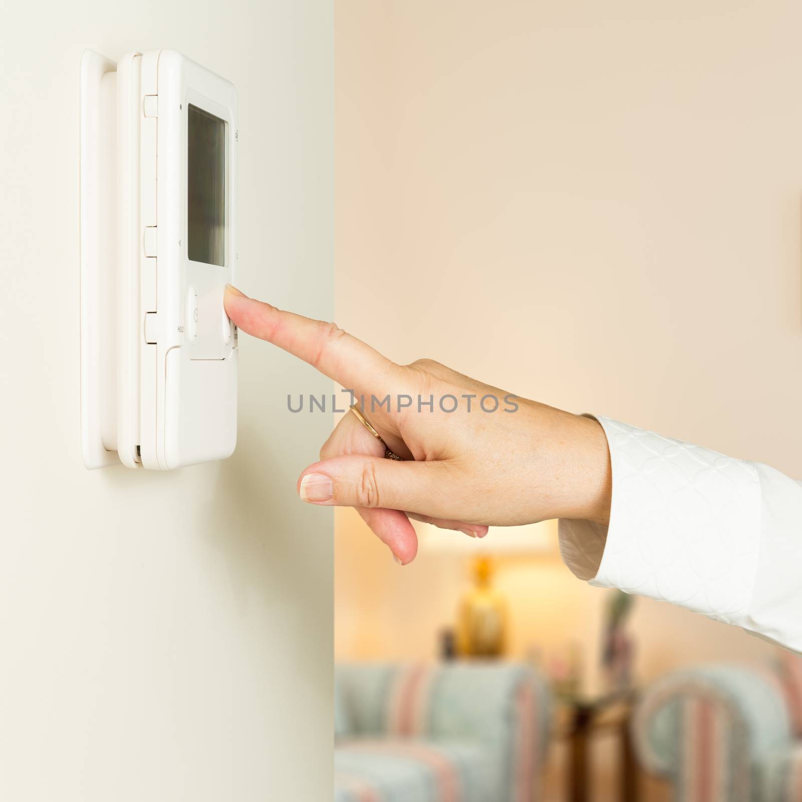 Caucasian lady pressing modern thermostat by steheap