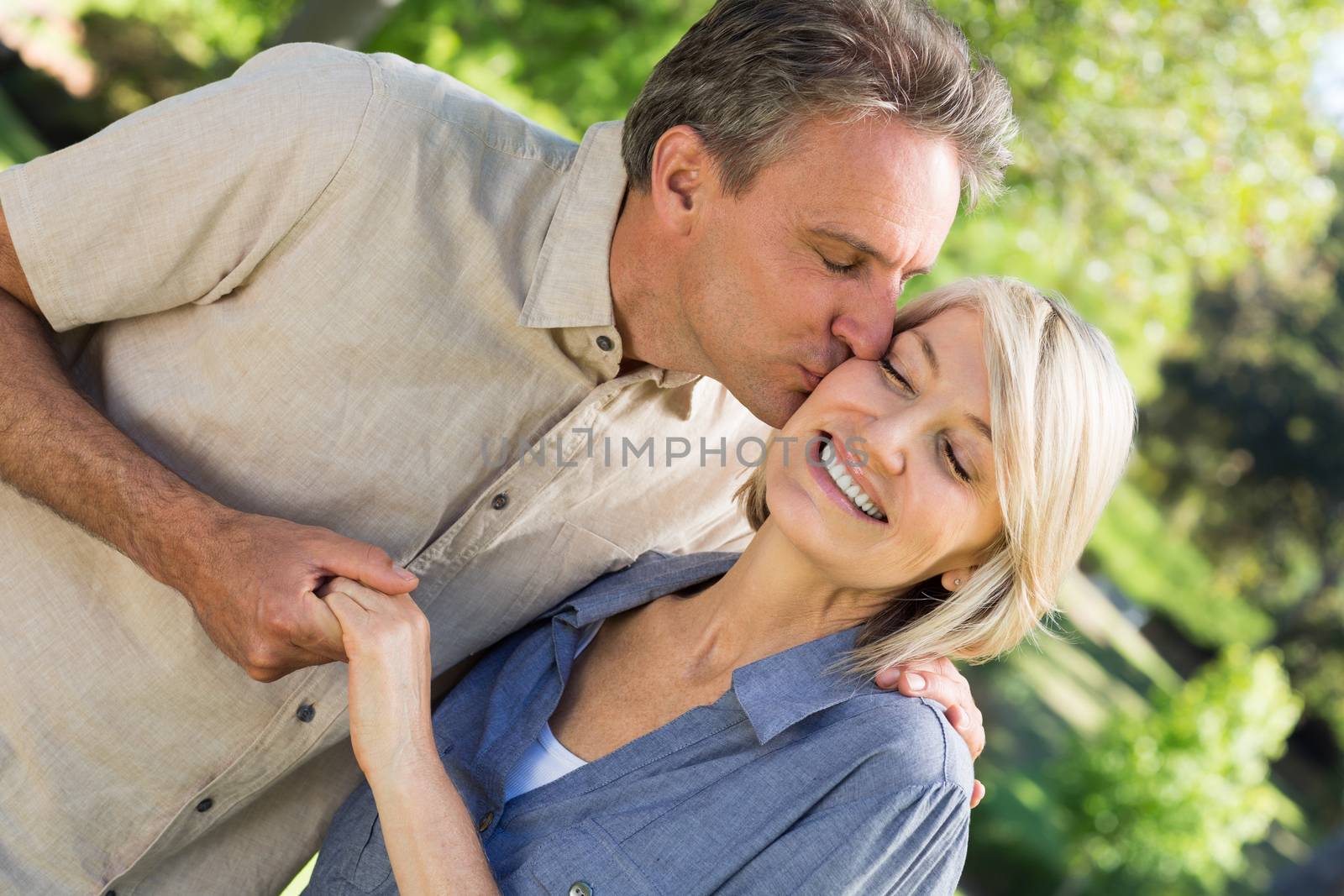 Romantic man kissing woman in park by Wavebreakmedia