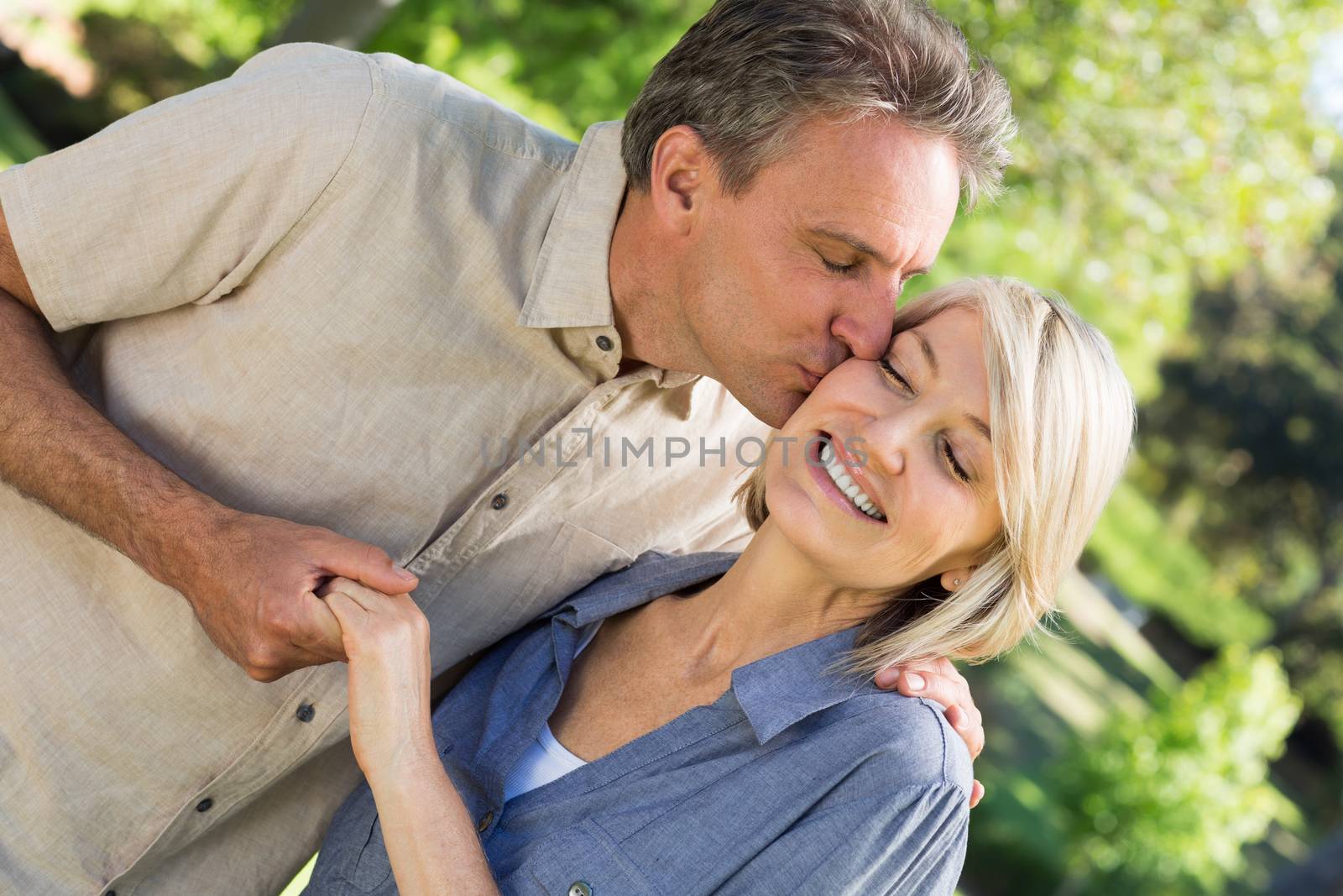 Romantic man kissing woman while holding hands in park