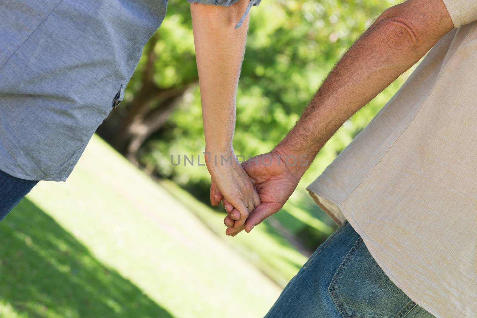 Midsection of romantic couple holding hands in park