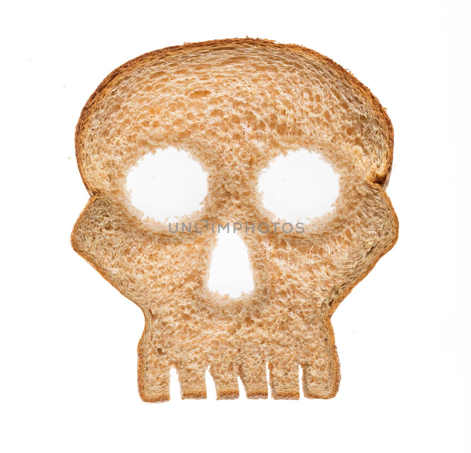 Skull shaped piece of bread cut from whole wheat loaf to illustrate danger from gluten in wheat products