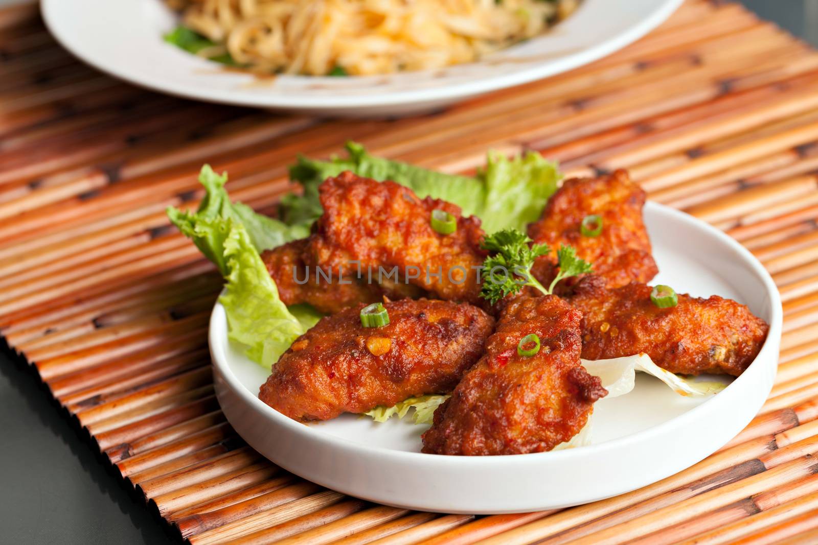 Thai style spicy chicken wings on a round white plate.