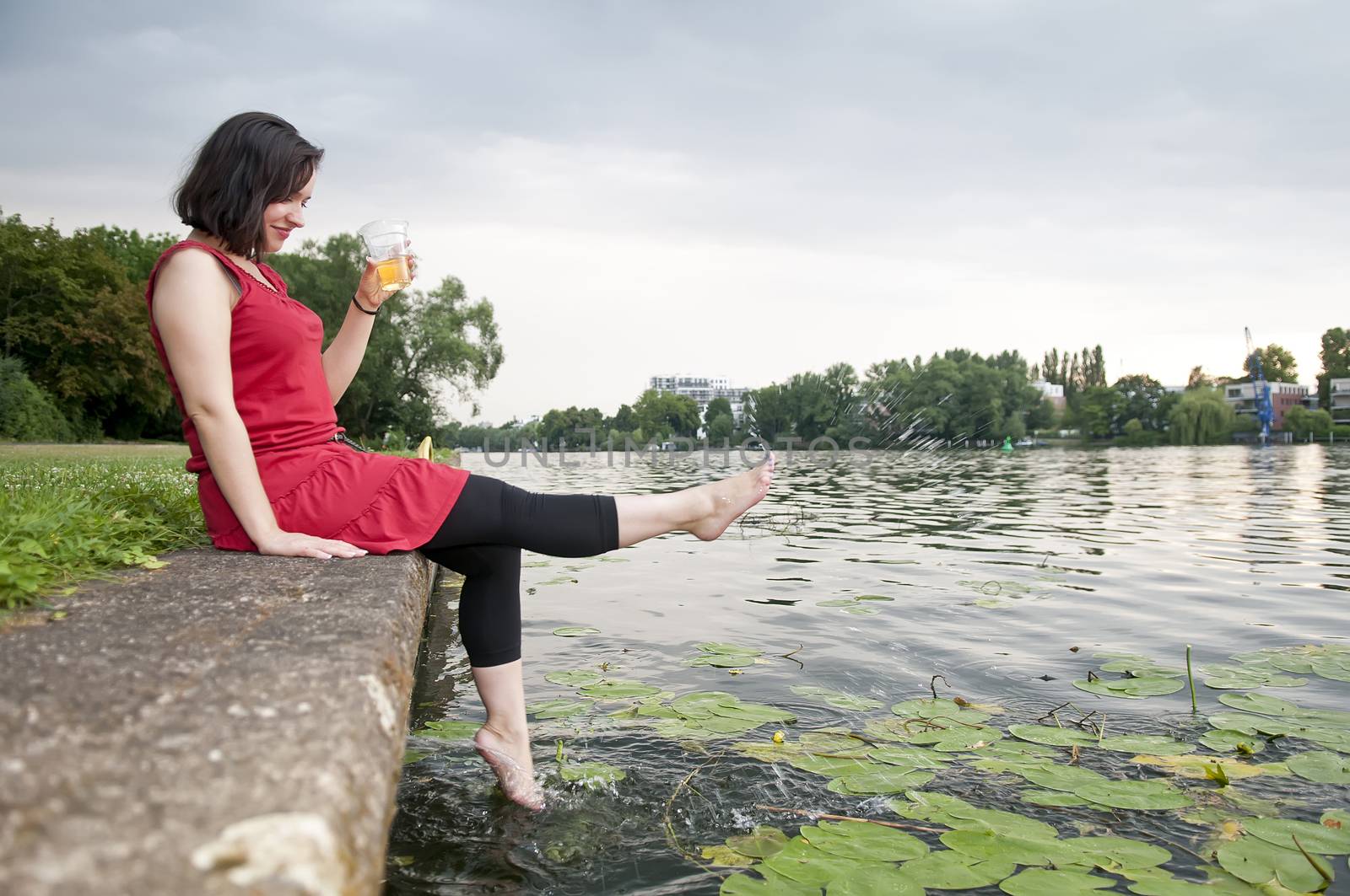 smiling young woman with beer sitting on the river